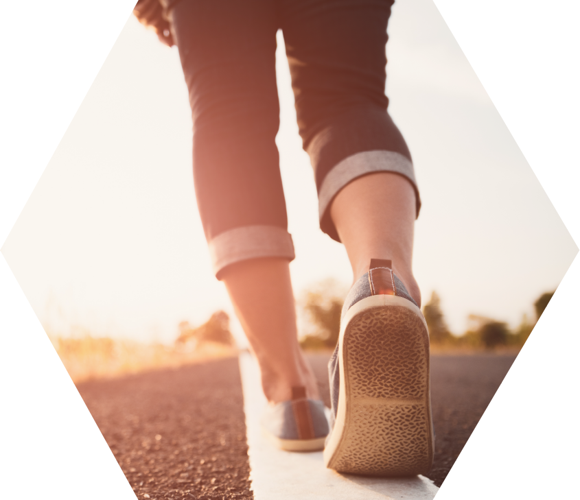 view of the lower legs of woman walking away down middle line of rural road