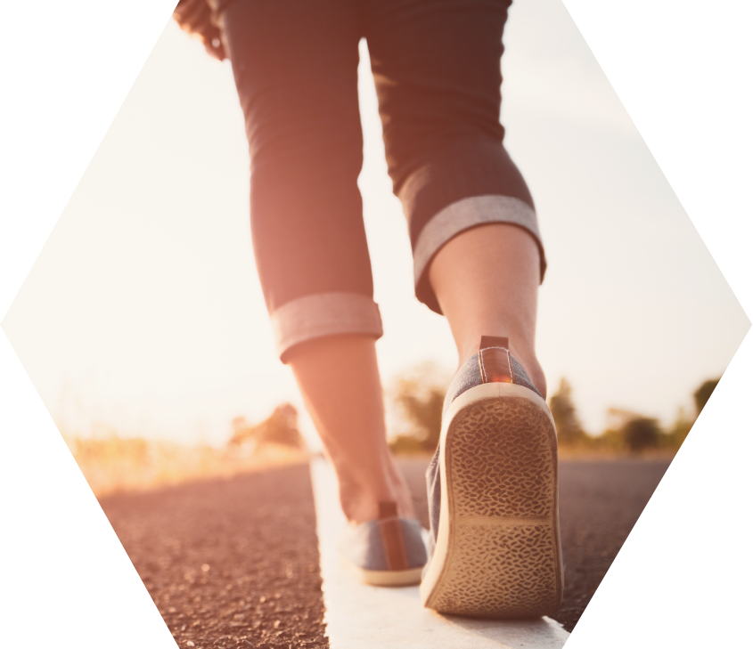 view of the lower legs of woman walking away down middle line of rural road