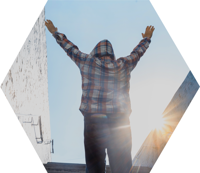 person in plaid flannel hoodie on stairs, facing away, with hands in air in triumph